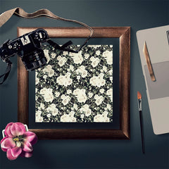 Wood-grained picture frame with a black and white floral pattern inside, next to a camera and art supplies | Shroomi