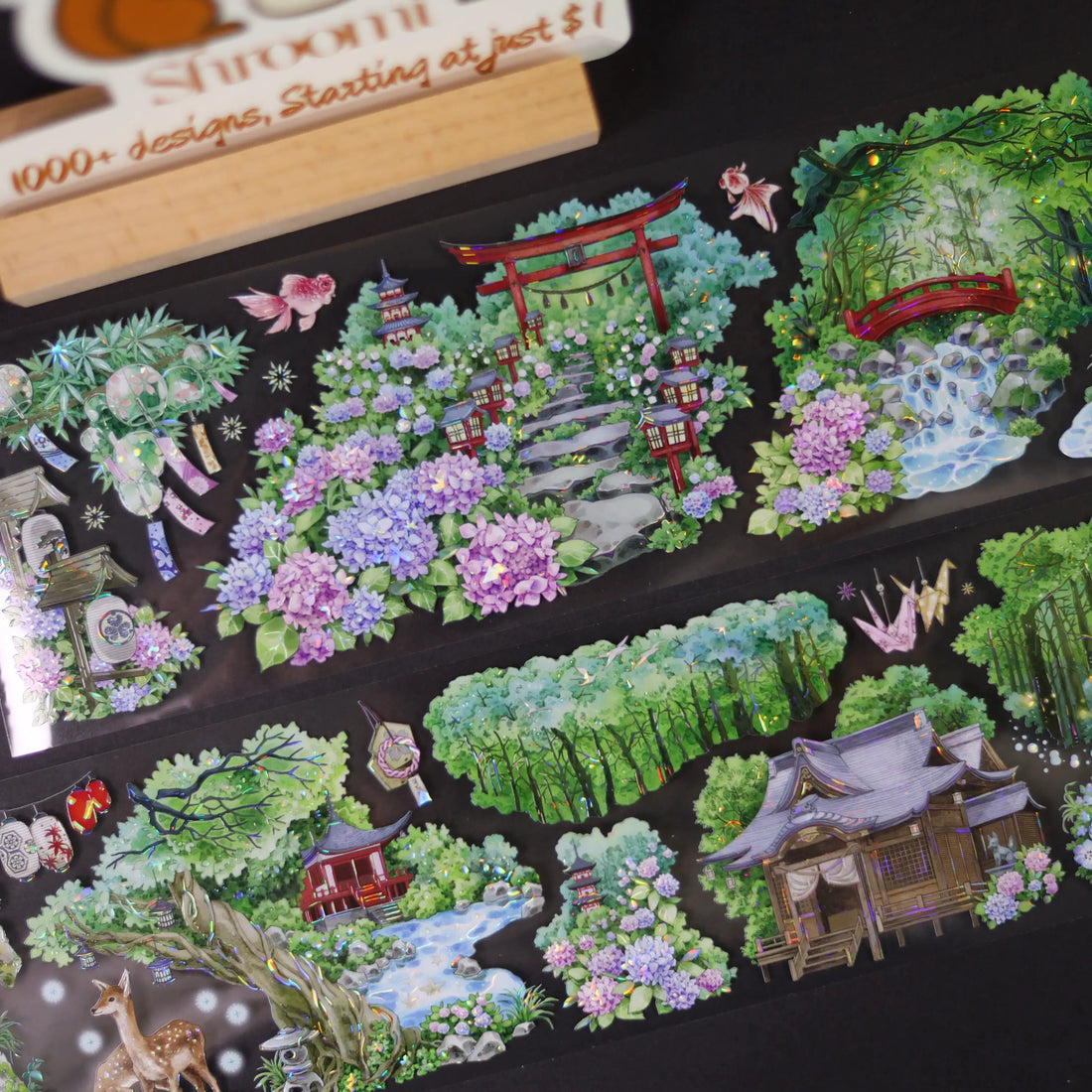 Decorative stickers with garden and nature designs on a black background, with a wooden stamp handle in the corner.