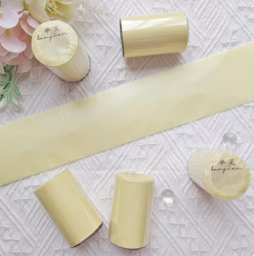 Wide solid red washi tape roll next to flowers — product styling shot