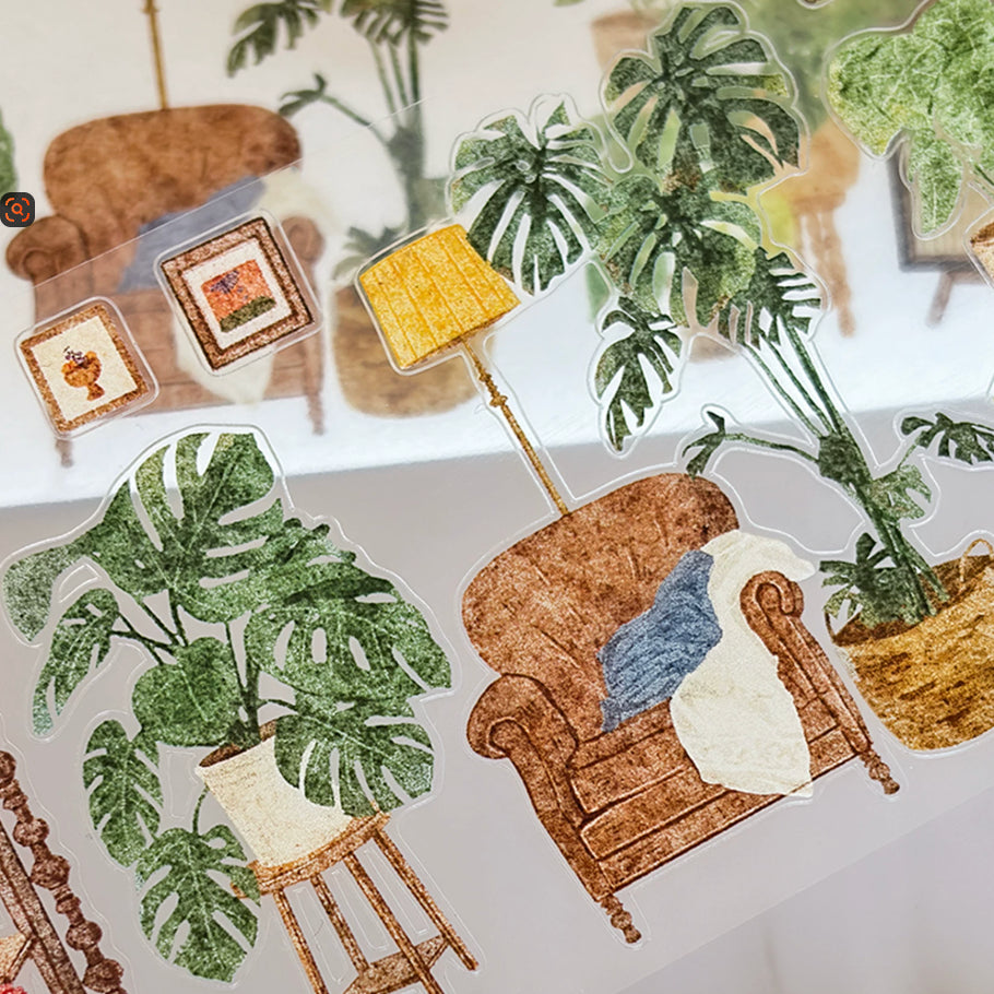 Transparent sticker roll with cozy home decor, armchairs, lamps, books, framed art, and leafy houseplants