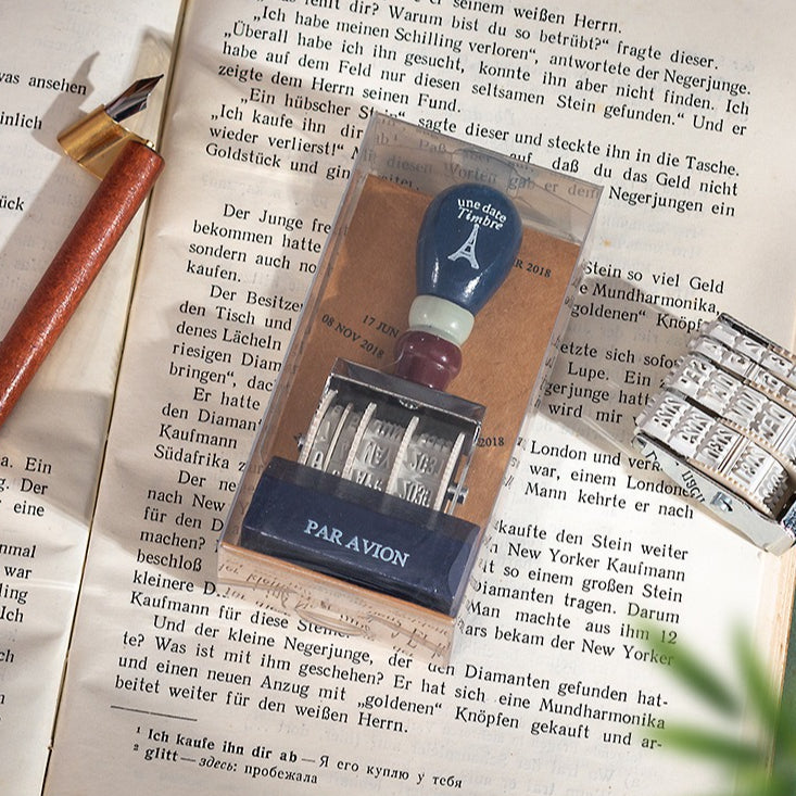 Vintage date roller stamp with wood-style handle, retro postal lettering, metal date wheels, and desk display base