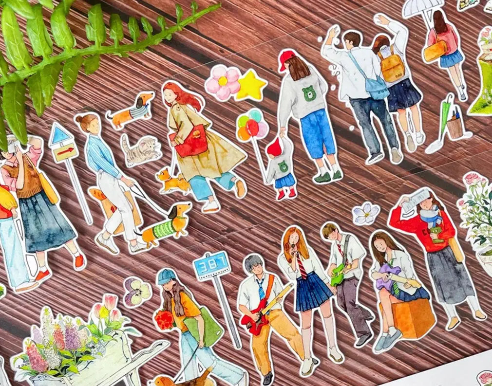 Die-cut Everyday Strolls characters on wood surface — individuals with bags, balloons, a guitarist, and pet dogs