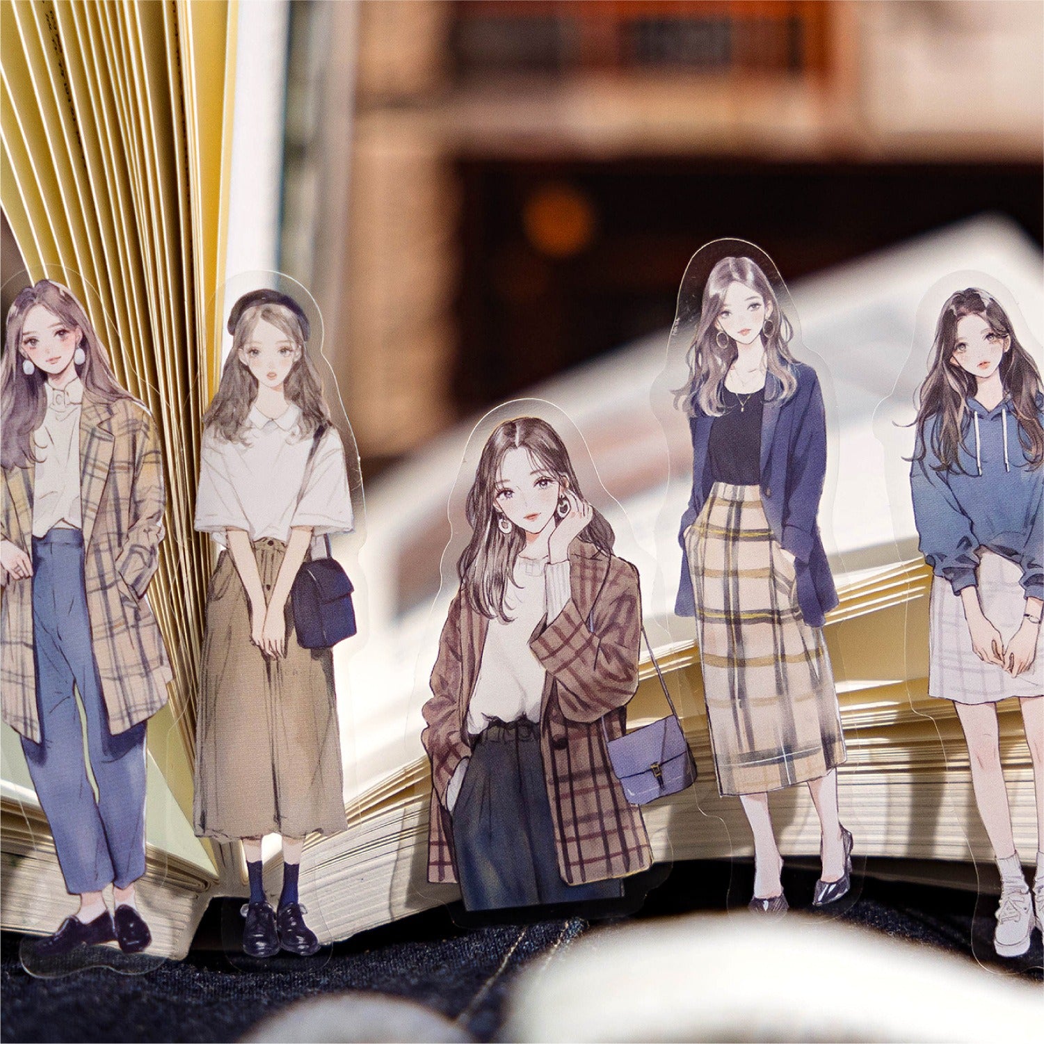 Five clear decorative anime girl stickers in trendy outfits, standing in an open journal, from Shroomi.