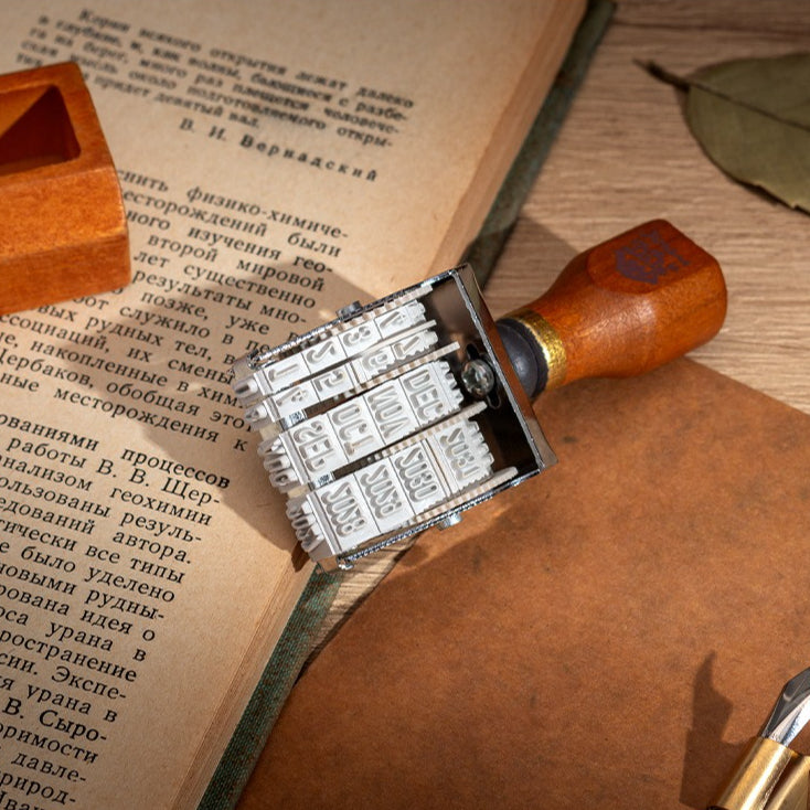 Vintage date roller stamp with wood-style handle, retro postal lettering, metal date wheels, and desk display base
