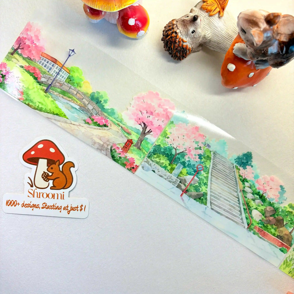 Charming PET scene-making tape featuring a watercolor countryside with cherry blossoms, cottages, bridges, and winding roads.