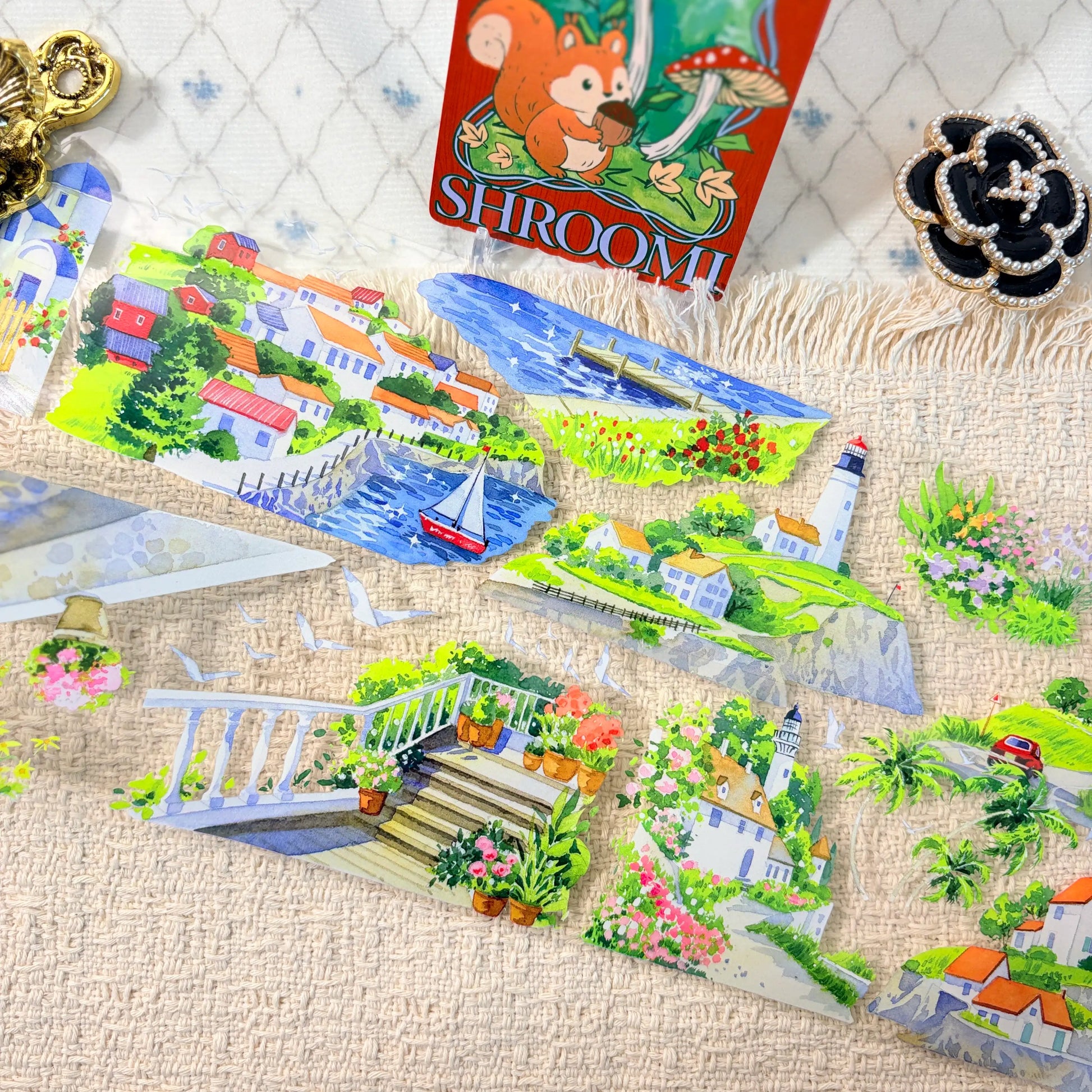 Blue seaside water, coastal homes, flowers, boats, and a lighthouse on decorative tape