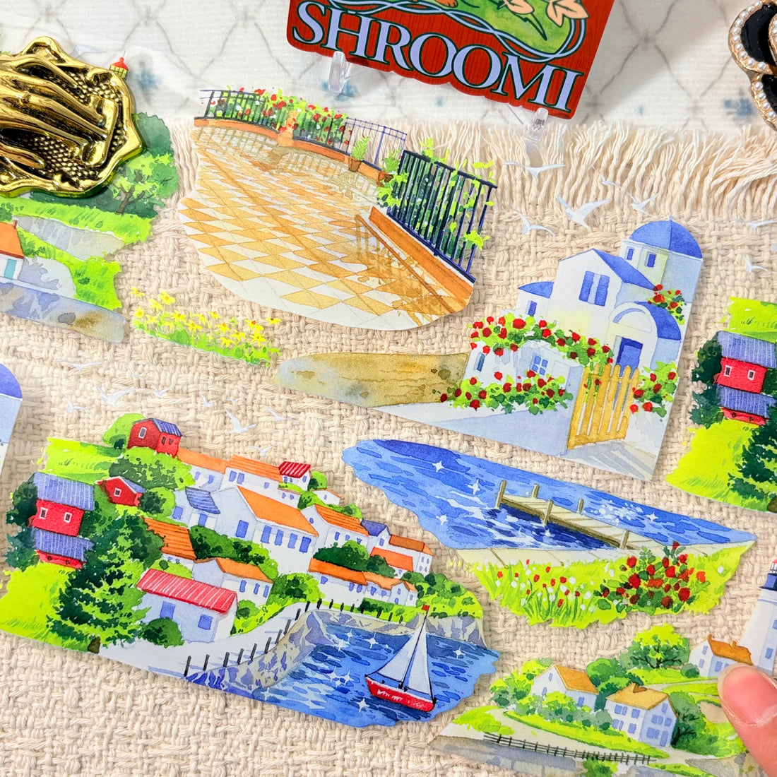 Blue seaside water, coastal homes, flowers, boats, and a lighthouse on decorative tape
