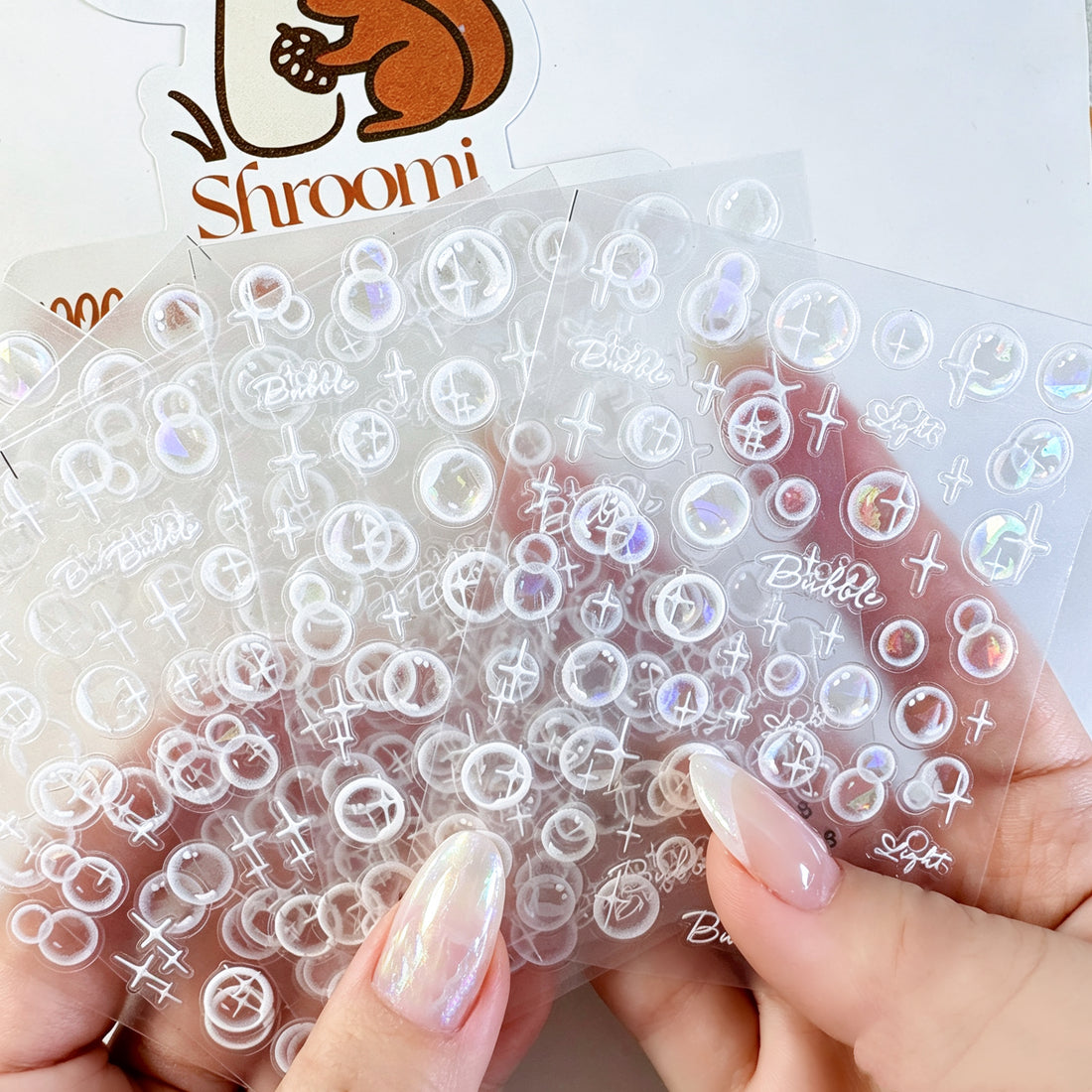 Five translucent iridescent bubble light sticker sheets with white sparkle accents