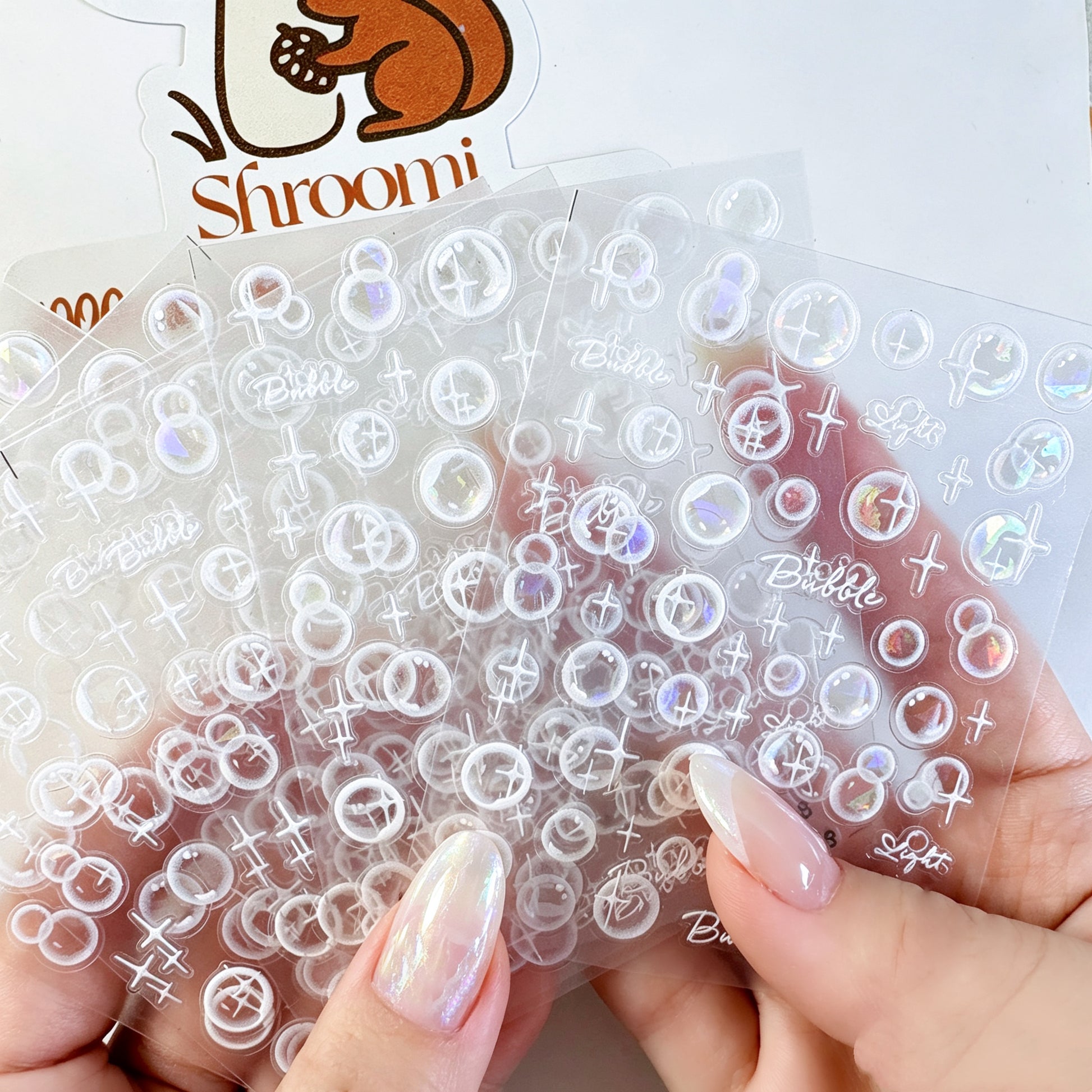 Five translucent iridescent bubble light sticker sheets with white sparkle accents