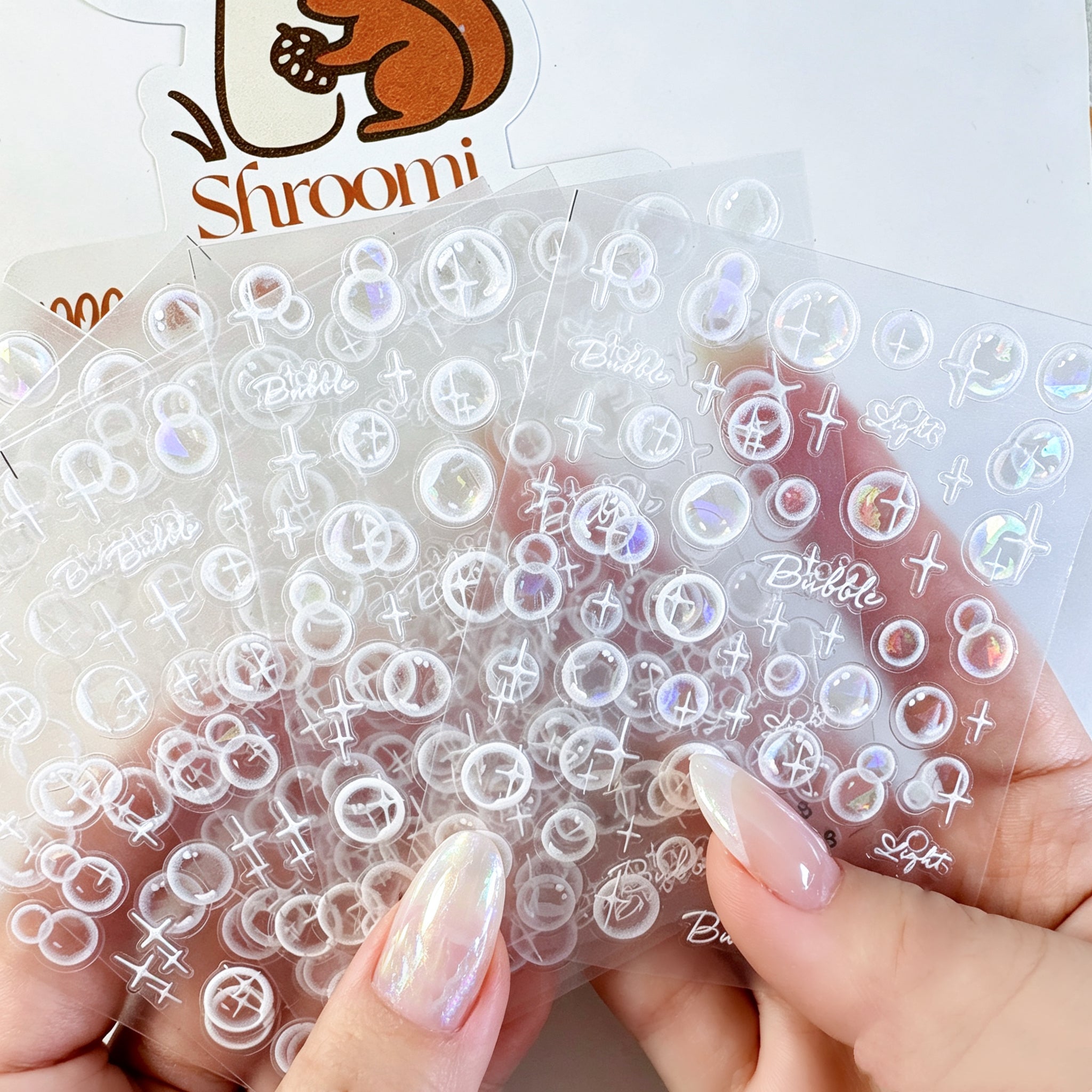 Five translucent iridescent bubble light sticker sheets with white sparkle accents