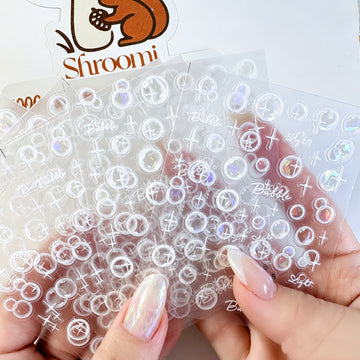 Five translucent iridescent bubble light sticker sheets with white sparkle accents