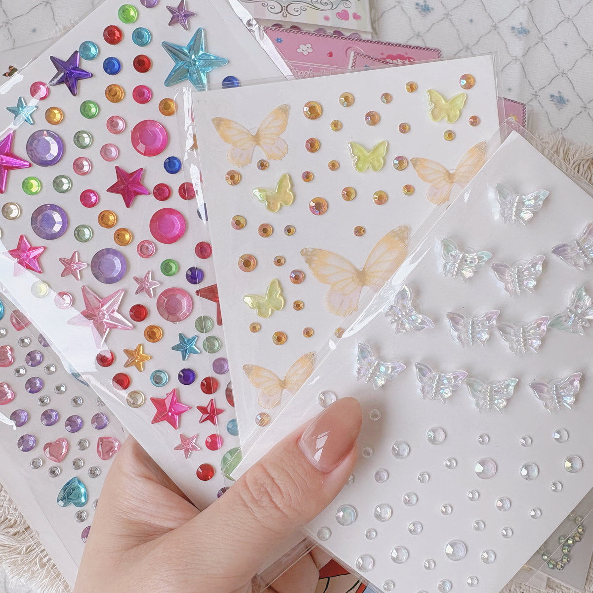 Hand holding star, butterfly and pearl rhinestone sticker sheets