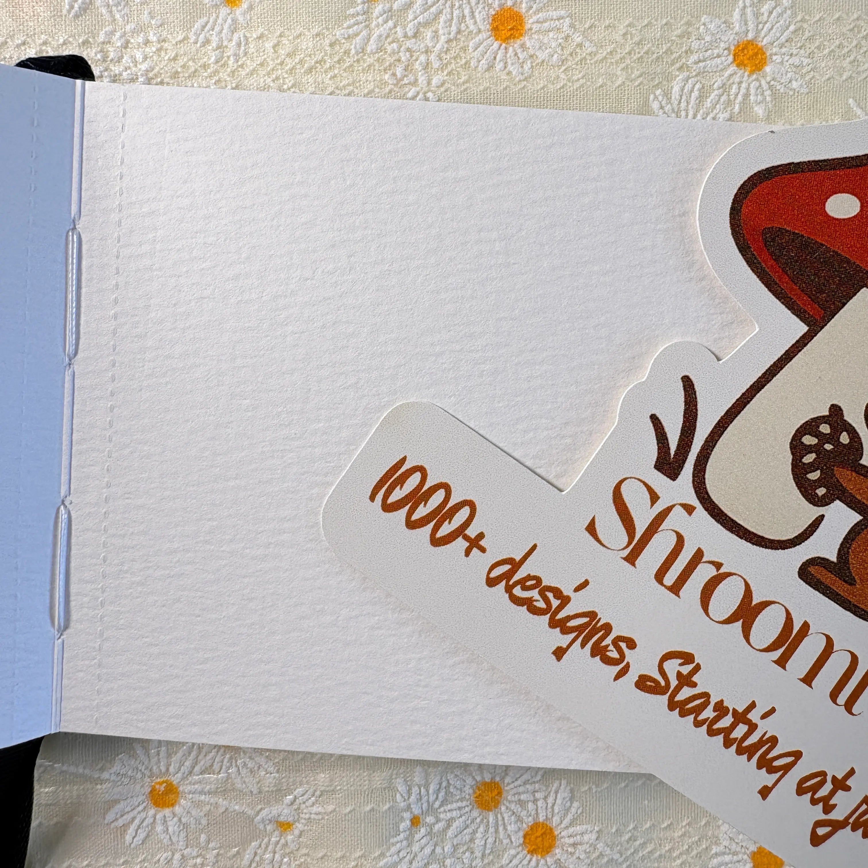 Hardcover techo journal notebook with elastic closure on daisy embroidered fabric background