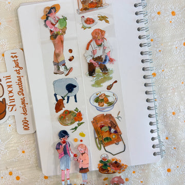 Shroomi PET tape on journal showing autumn harvest farm scenes: girl carrying squash, boy fishing in stream, white sheep with autumn leaves, soup bowl with vegetables, children eating apples, wooden harvest cart piled with produce