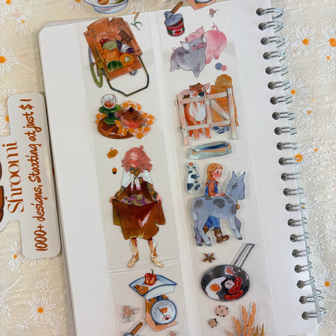 Shroomi PET tape on journal showing autumn harvest farm scenes: girl carrying squash, boy fishing in stream, white sheep with autumn leaves, soup bowl with vegetables, children eating apples, wooden harvest cart piled with produce