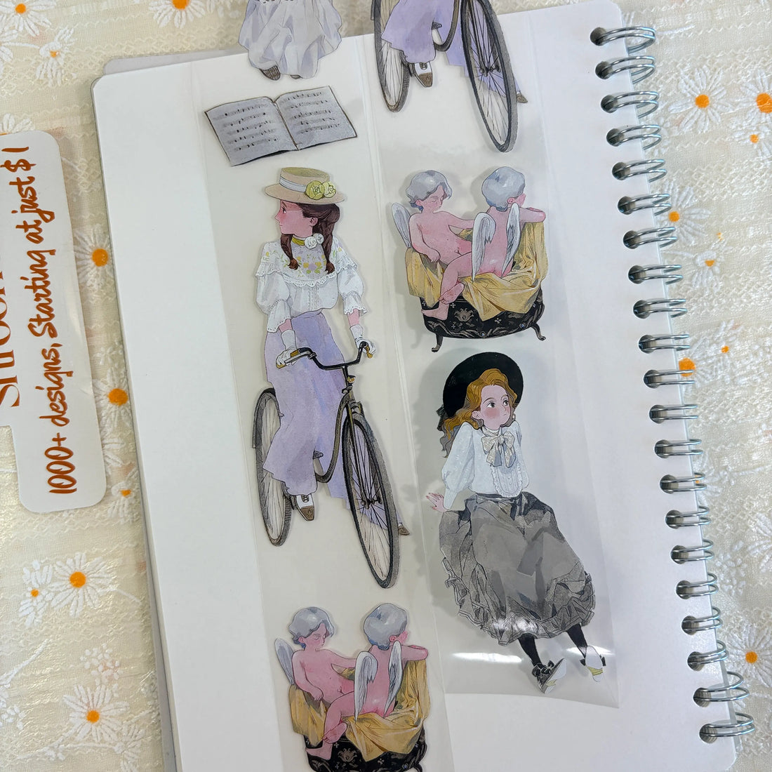 Shroomi PET tape on journal showing vintage Edwardian figures: girl in purple skirt with bicycle, cherubs on chaise, girl in gray tulle skirt, open sheet music book