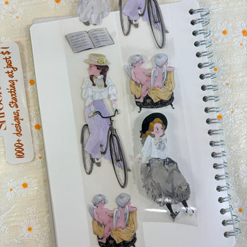 Shroomi PET tape on journal showing vintage Edwardian figures: girl in purple skirt with bicycle, cherubs on chaise, girl in gray tulle skirt, open sheet music book