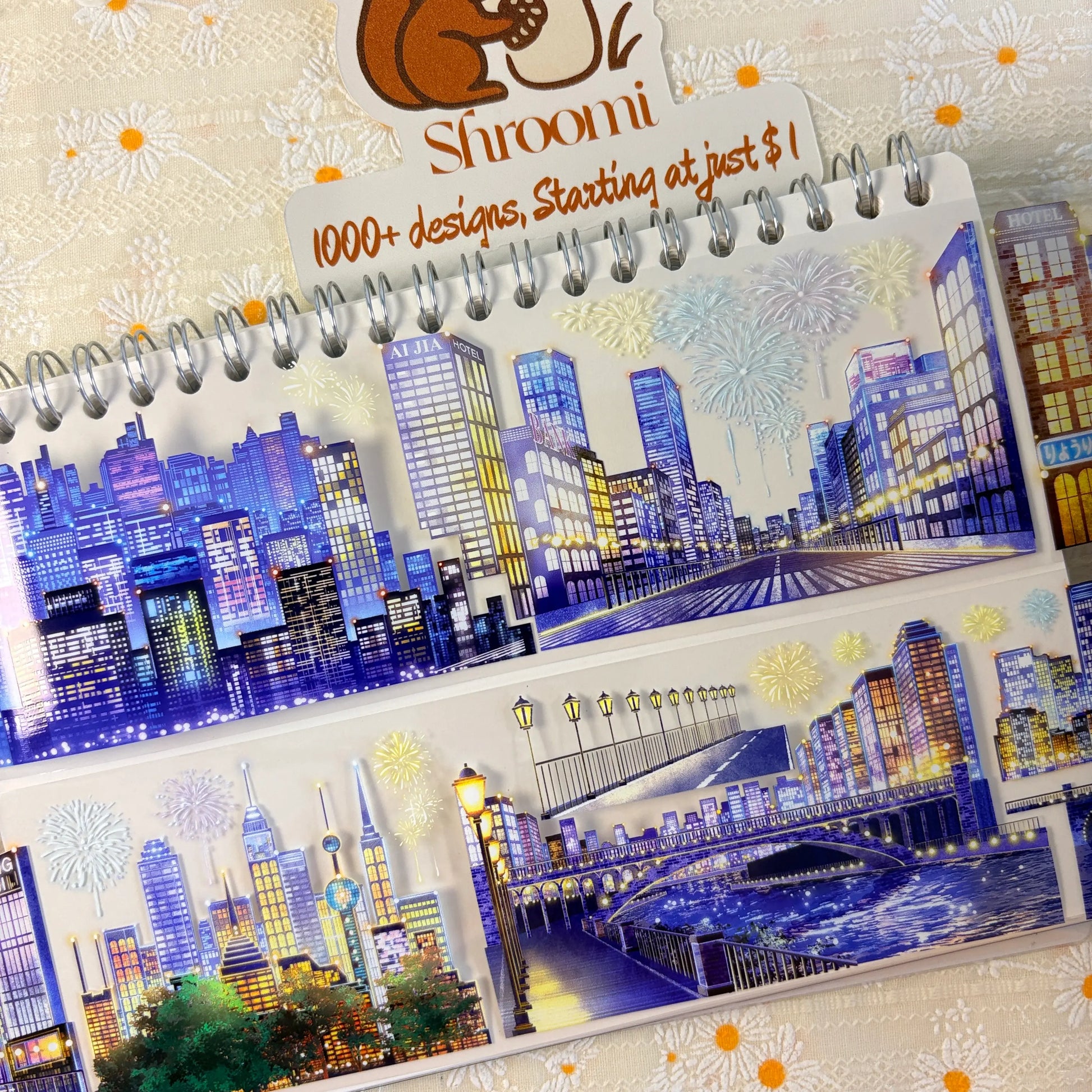 Shroomi Night City Shimmer PET tape on journal — two strips: blue-purple skyscrapers with fireworks (top); illuminated bridge with lamp posts over a sparkling waterway and city skyline (bottom)