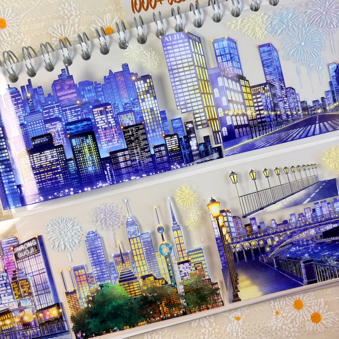 Shroomi Night City Shimmer PET tape on journal — two strips: blue-purple night skyline with illuminated skyscrapers and fireworks (top); city skyline with communications tower, fireworks, and lamp-lit bridge over water (bottom)