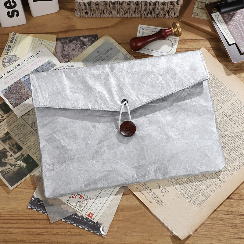 Silver textured envelope clutch with a wooden button closure on a wooden table with papers and a wax seal | Shroomi