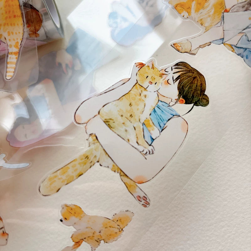 Die-cut girls hugging cats and dogs tape pieces layered on white paper