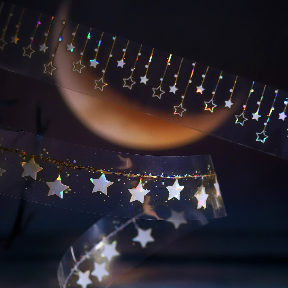 Shimmering star garland tape in front of a glowing moon