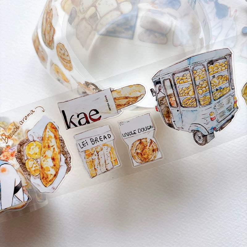 Die-cut bakery girls and bread tape pieces layered on white paper