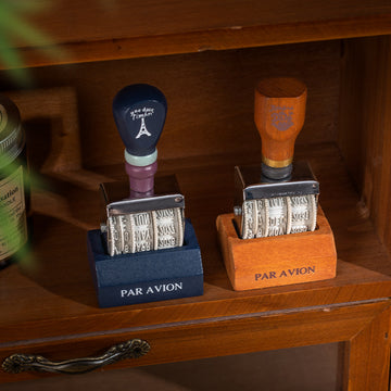 Vintage date roller stamp with wood-style handle, retro postal lettering, metal date wheels, and desk display base
