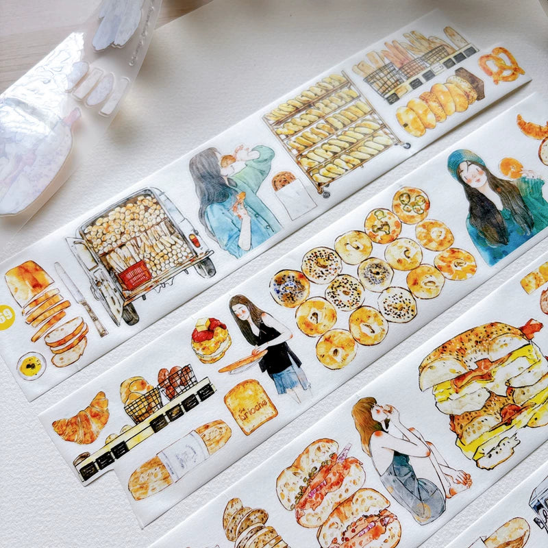 Die-cut bakery girls and bread tape pieces layered on white paper