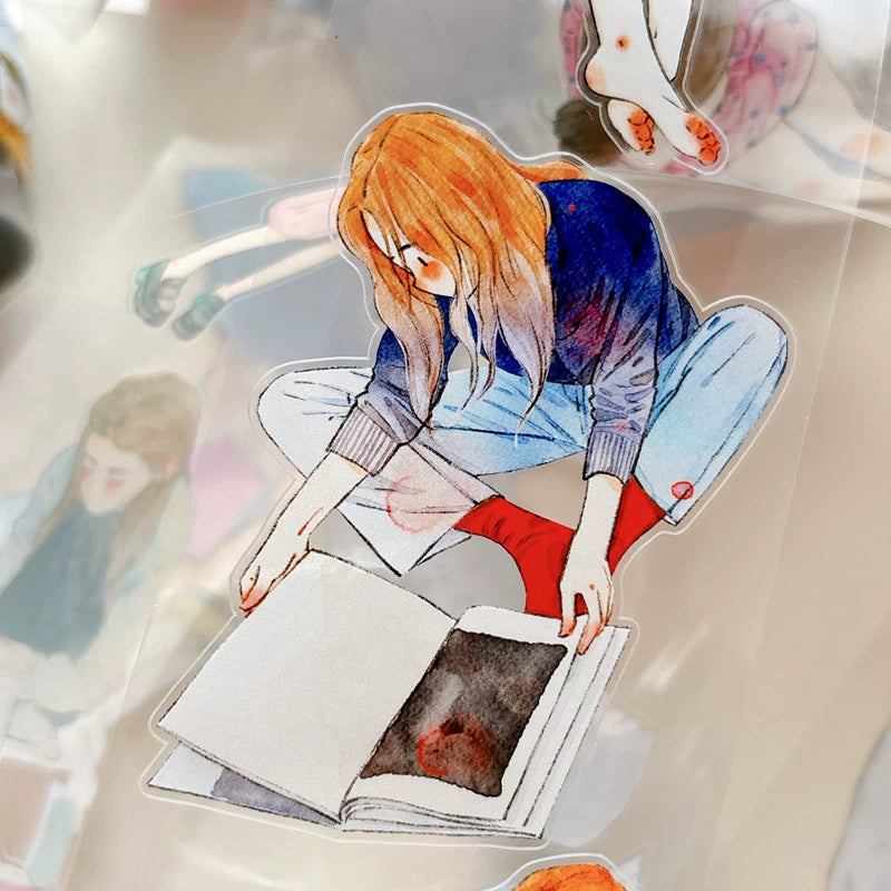 Die-cut girls reading books tape pieces layered on white paper
