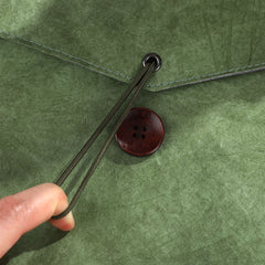 Close up of a green textured fabric with a wooden button and drawstring closure | Shroomi