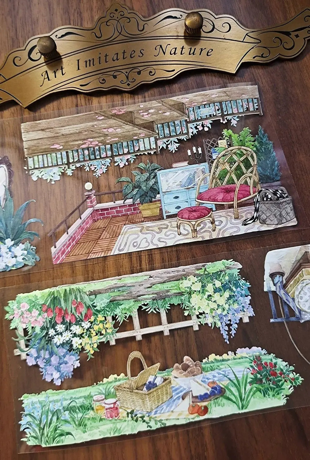 Window Garden View tape strips on wood surface — a terrace scene with wicker furniture and plants, a floral garden border, and a picnic basket in a flower garden