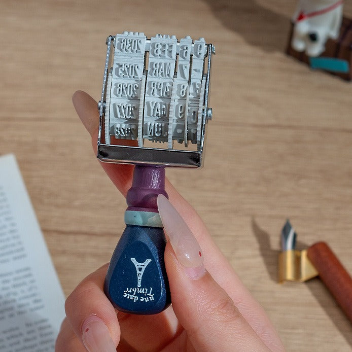 Vintage date roller stamp with wood-style handle, retro postal lettering, metal date wheels, and desk display base