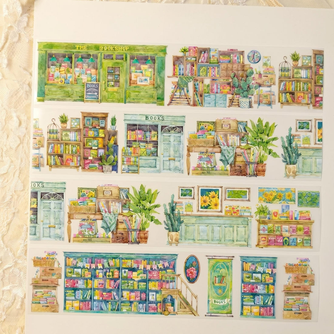 Watercolor PET tape artwork with cozy bookshop storefronts, stacked bookshelves, plants, and reading corners